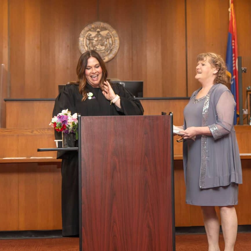 Judge Courtney Wachal smiles behind a podium with a graduate of the Kansas City Wellness Court