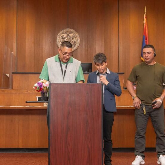 Three men stand behind a podium during Kansas City Wellness Court graduation