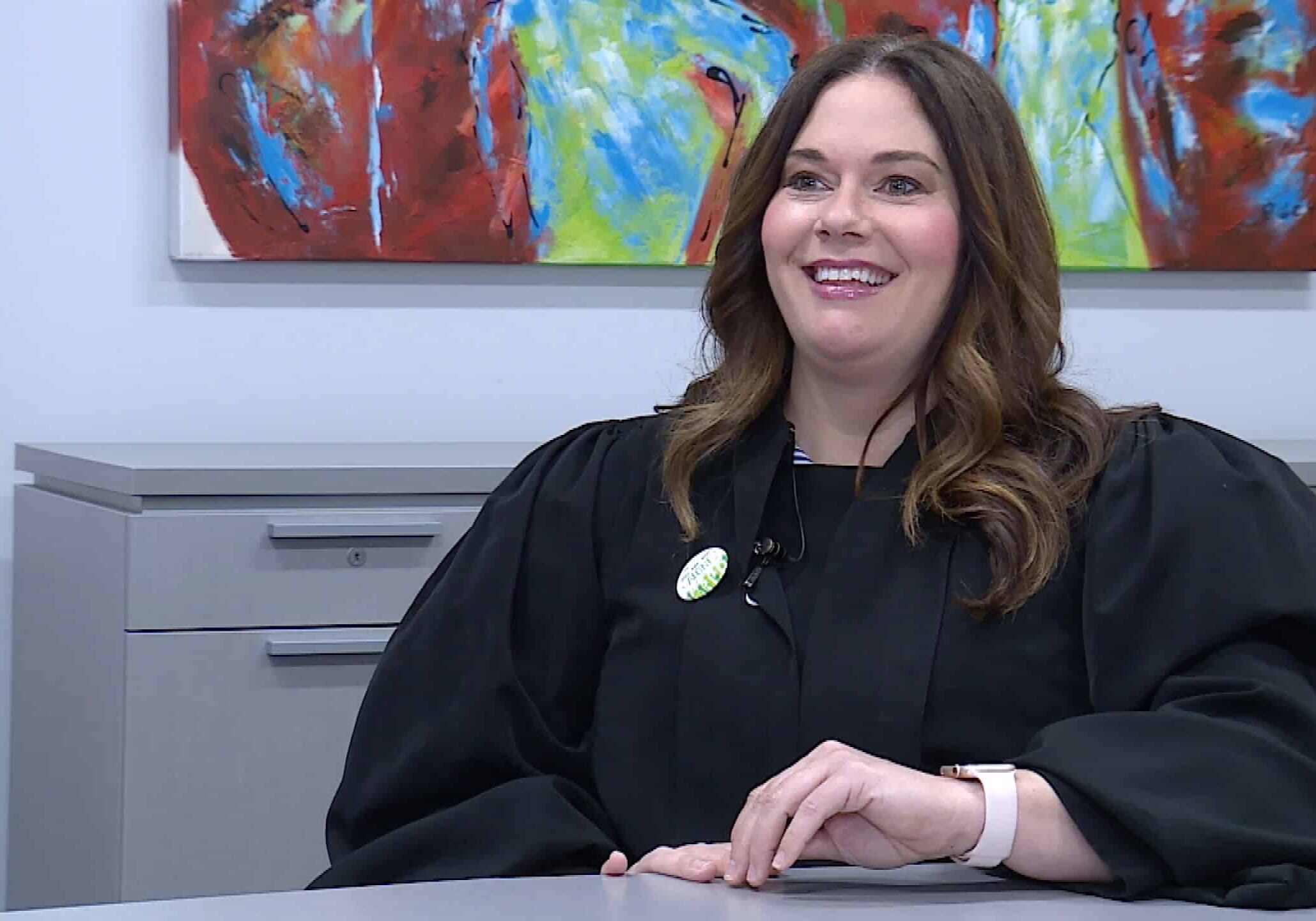 Judge Courtney Wachal smiling in a conference room in front of a colorful painting during an interview on KSHB