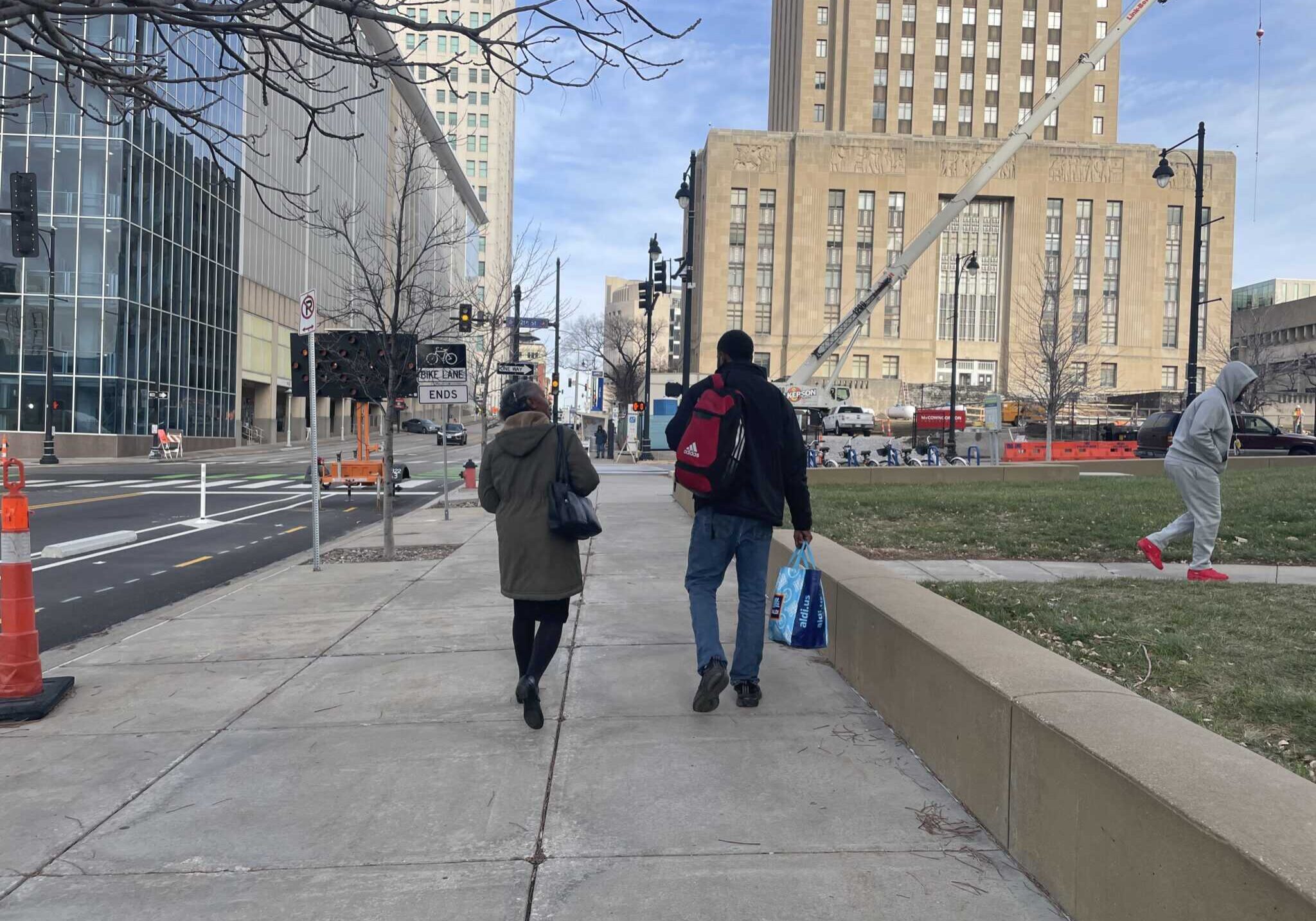Two people walking on the sidewalk toward the Kansas City courthouse